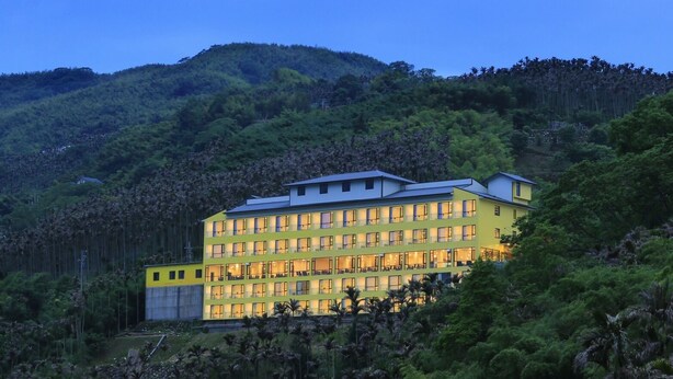 A multi-story hotel with a flat roof, surrounded by dense forest and hills. - Tai An Cingjing (Zhushan)