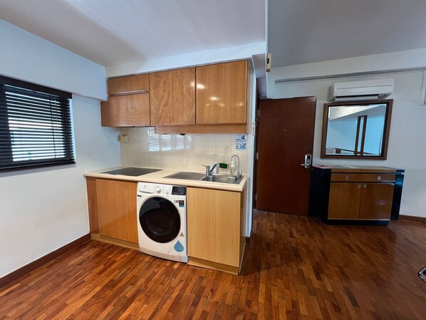 Une cuisine compacte avec des meubles en bois, un lave-linge encastré, un évier et un petit plan de travail.