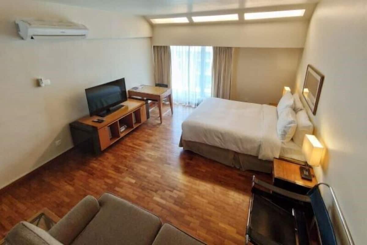 A hotel room with a bed, a TV, a desk, and a chair.