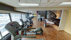 A gym with treadmills, ellipticals, and a staircase.