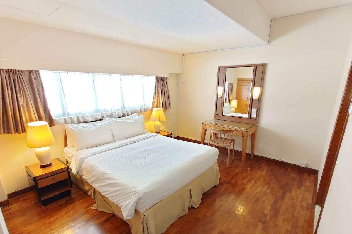 A hotel room with a large bed, two bedside lamps, a wooden desk, and a mirror.