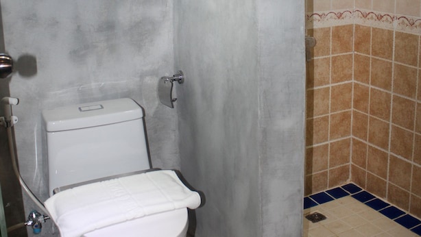 A small bathroom with a toilet, a window, and tiled walls. - Davita Boutique Hotel (Luang Prabang)