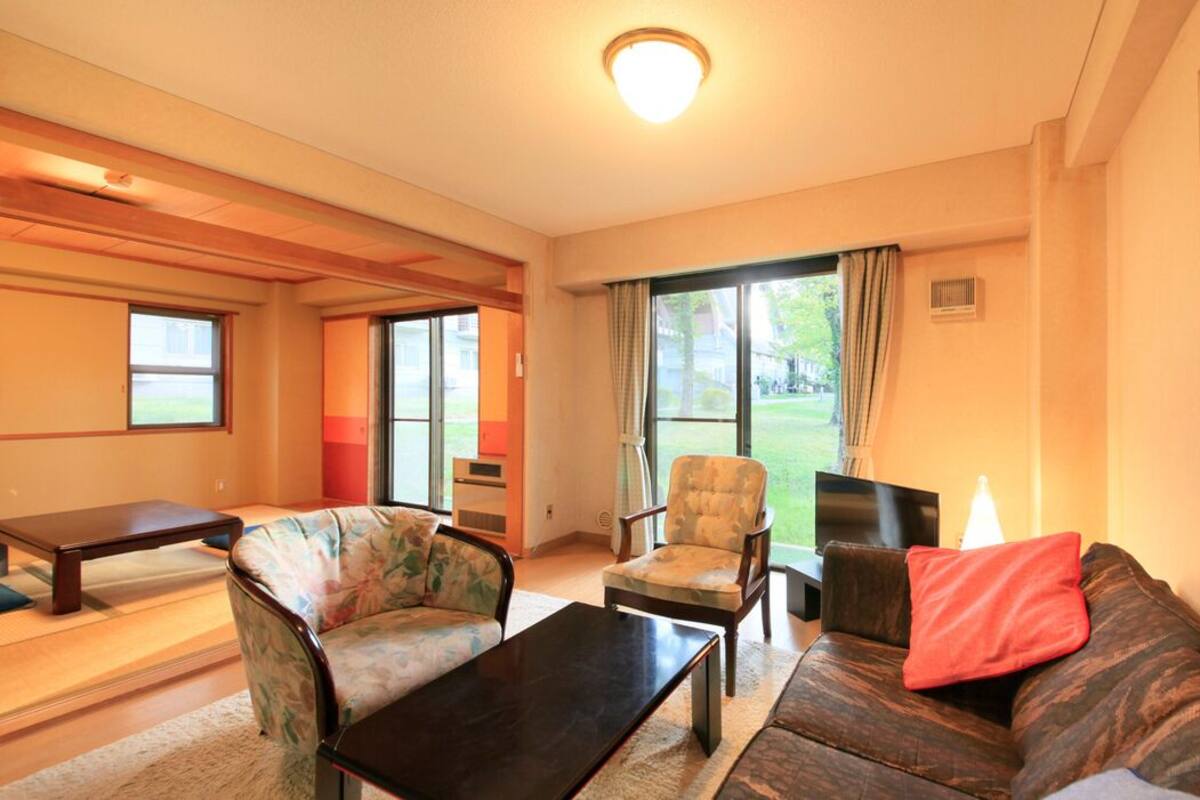A living room with a sofa, armchair, coffee table, and a dining table.