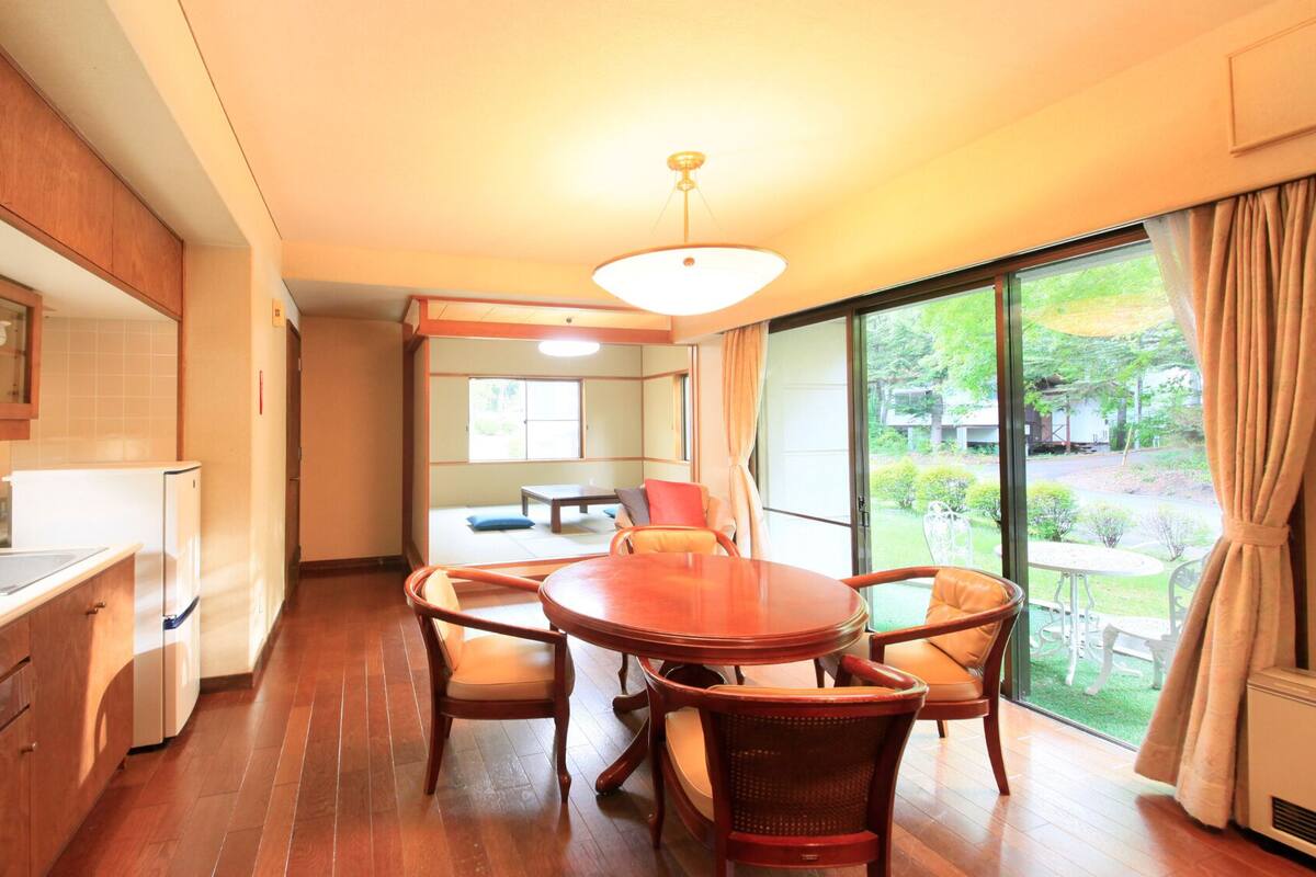 A compact kitchen with a dining area, a large window, and a view of the garden.