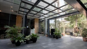 Un espacio interior amplio con techo de vidrio, plantas en macetas y una zona de estar.