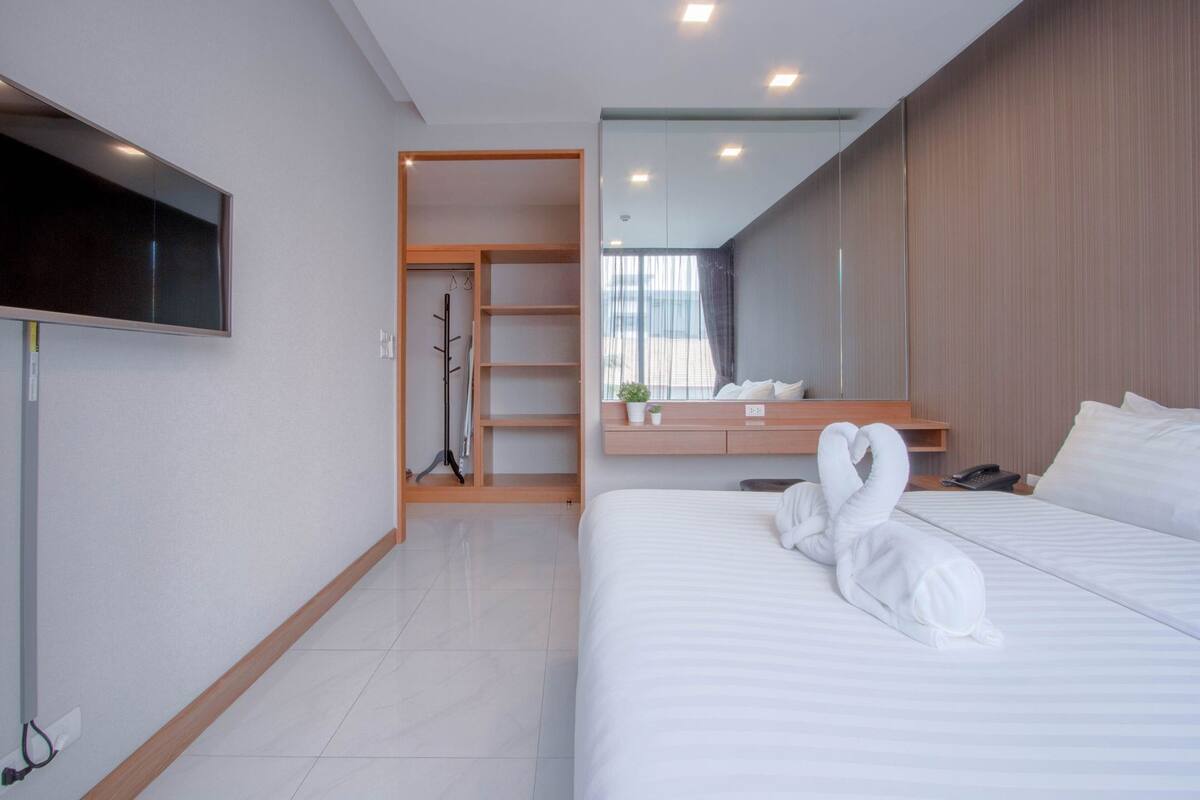 A hotel room with a bed, a TV, a wardrobe, and a mirror.