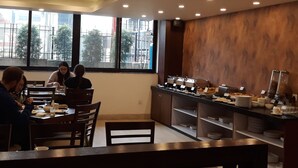 Un restaurante con decoración moderna, que presenta una larga barra con diversas opciones de comida y una zona de estar con mesas y sillas.