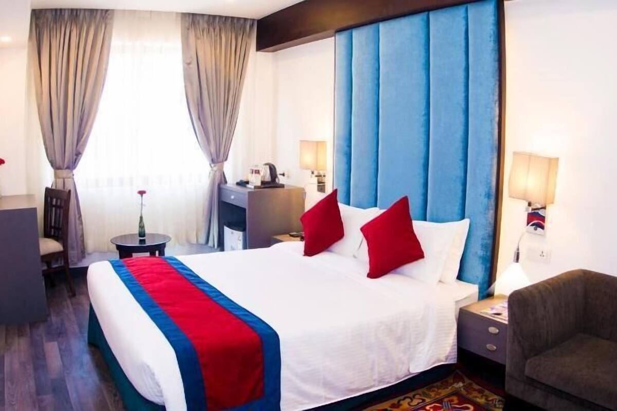 A hotel room with a bed, a desk, a chair, and a nightstand.