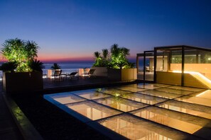 A rooftop terrace with a glass floor, seating area, and a glass-enclosed structure. - The Erawan Koh Chang (Ko Chang)