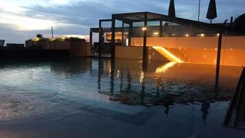 Un área de piscina moderna con una estructura de vidrio y una fuente de agua.