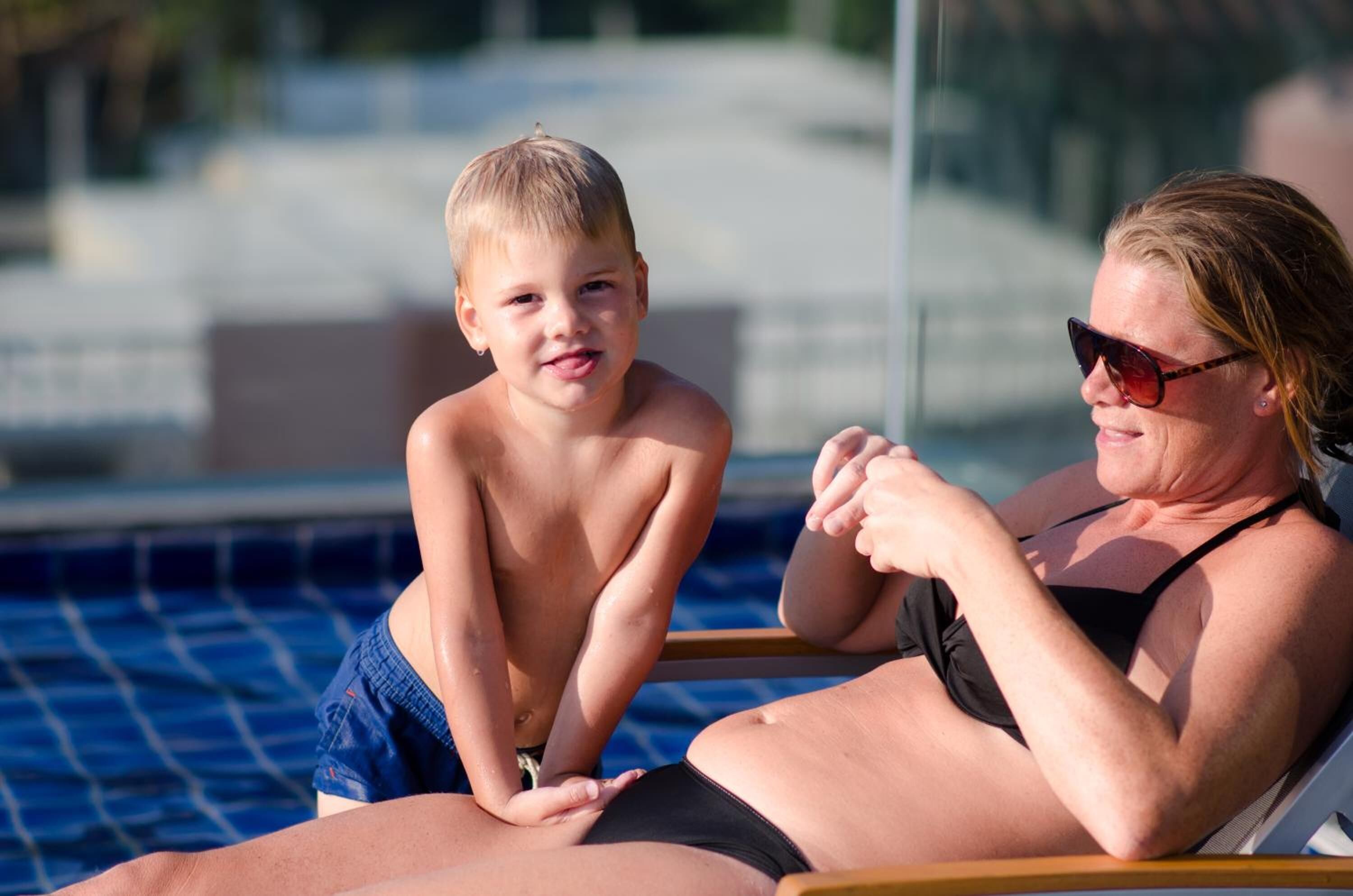 Une scène se déroulant au bord d’une piscine, avec un enfant et un adulte.