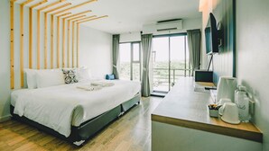 Une chambre d’hôtel moderne dotée d’un grand lit, d’un bureau avec un téléviseur à écran plat et d’un balcon avec des rideaux.