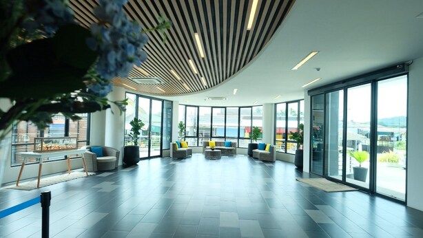 Un hall d’entrée spacieux, doté de mobilier moderne, de grandes fenêtres et offrant une vue sur la ville.