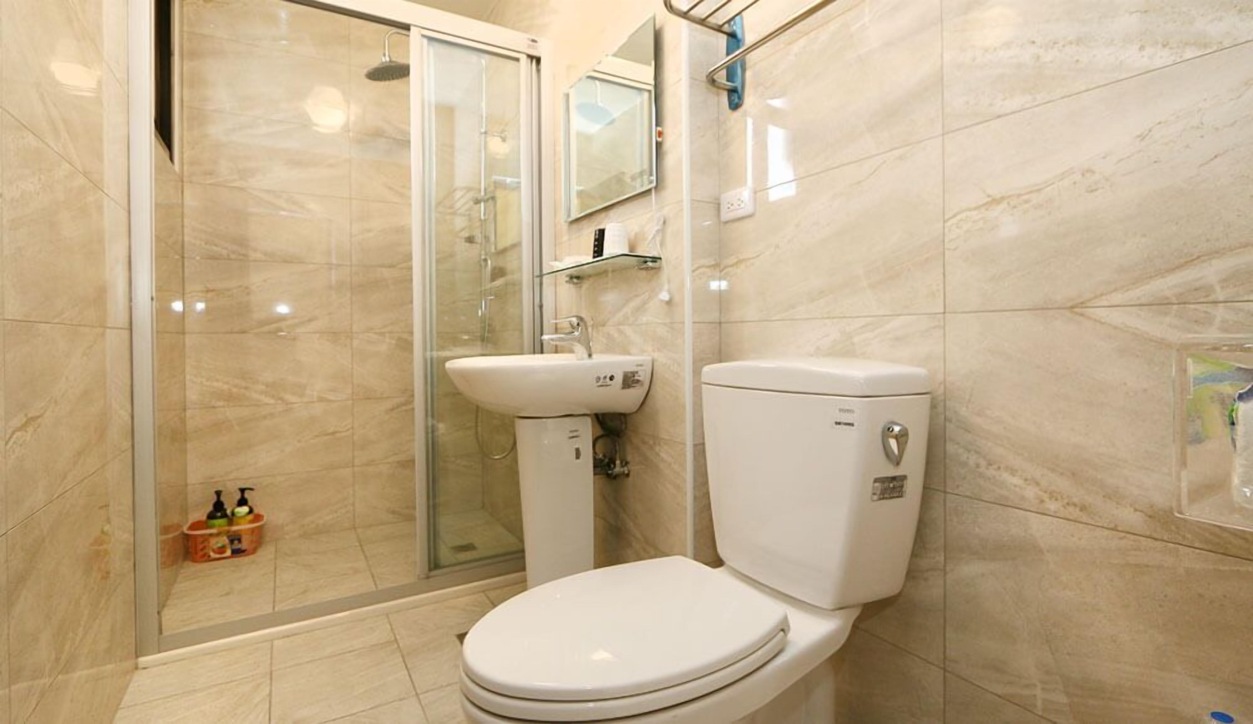 A modern bathroom with a glass-enclosed shower, a white toilet, and a sink.