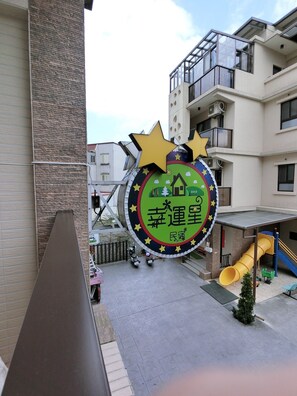 A building with a large sign featuring stars and a house, a yellow slide, and a small tree. - Luckystar B&B (Luodong)