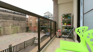 A balcony with a view of a cityscape, a metal shelf with plants, and a bright green chair. - Luckystar B&B (Luodong)