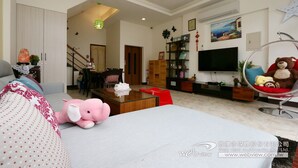 A spacious living room with a large bed, a coffee table, a TV, and a teddy bear in a hanging chair. - Luckystar B&B (Luodong)
