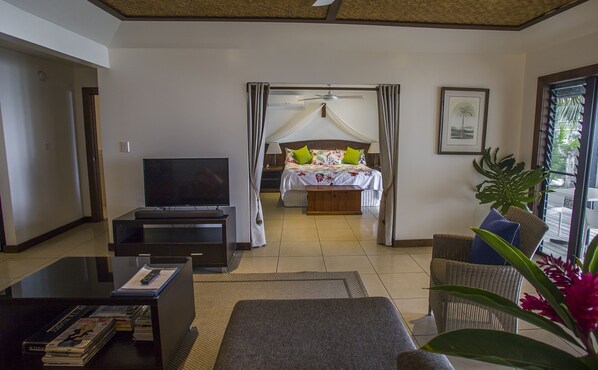 A hotel room with a bed, a TV, a desk with books, and a large window with curtains.