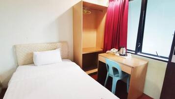 Una habitación de hotel con cama, escritorio, silla, armario y ventana con cortinas.