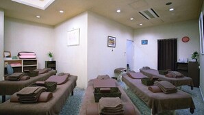 Una habitación con camillas de masaje, una recepción y un ventanal con cortinas.