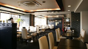 Un restaurante con varias mesas y sillas, una zona de bar y una pared de ladrillo.