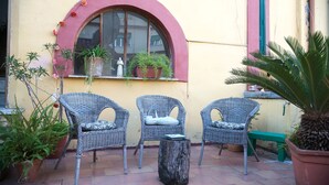 A patio with wicker chairs, a wooden table, and potted plants. - B&B Cuore di Napoli (Naples)