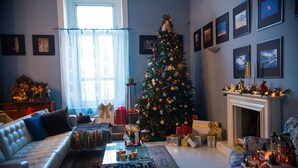 A living room with a Christmas tree, a fireplace, and framed pictures on the wall. - B&B Cuore di Napoli (Naples)