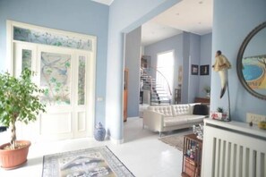 A spacious living room with a white sofa, a staircase, and a large window. - B&B Cuore di Napoli (Naples)