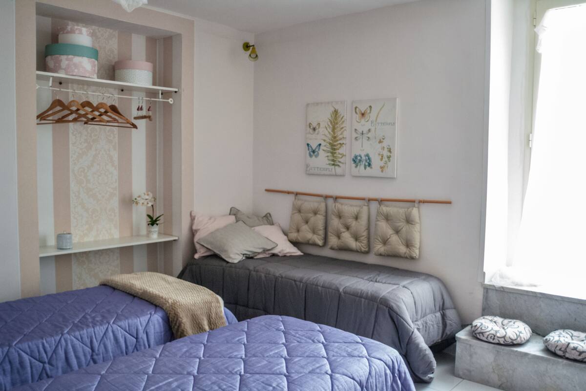A bedroom with two beds, a wardrobe, and a window.