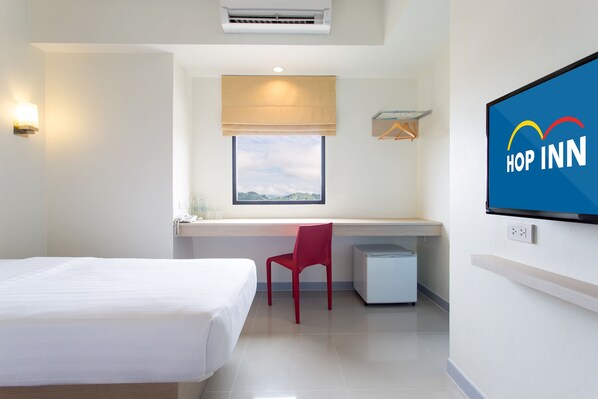 A hotel room with a bed, a desk, a chair, a TV, and a window with a view.