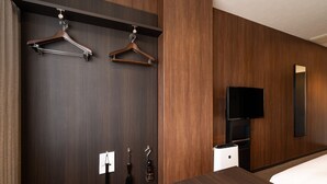 Una habitación de hotel con un armario de madera oscura, una cama, un televisor y un espejo.