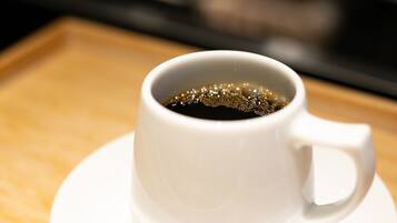 A white cup of coffee on a white saucer.