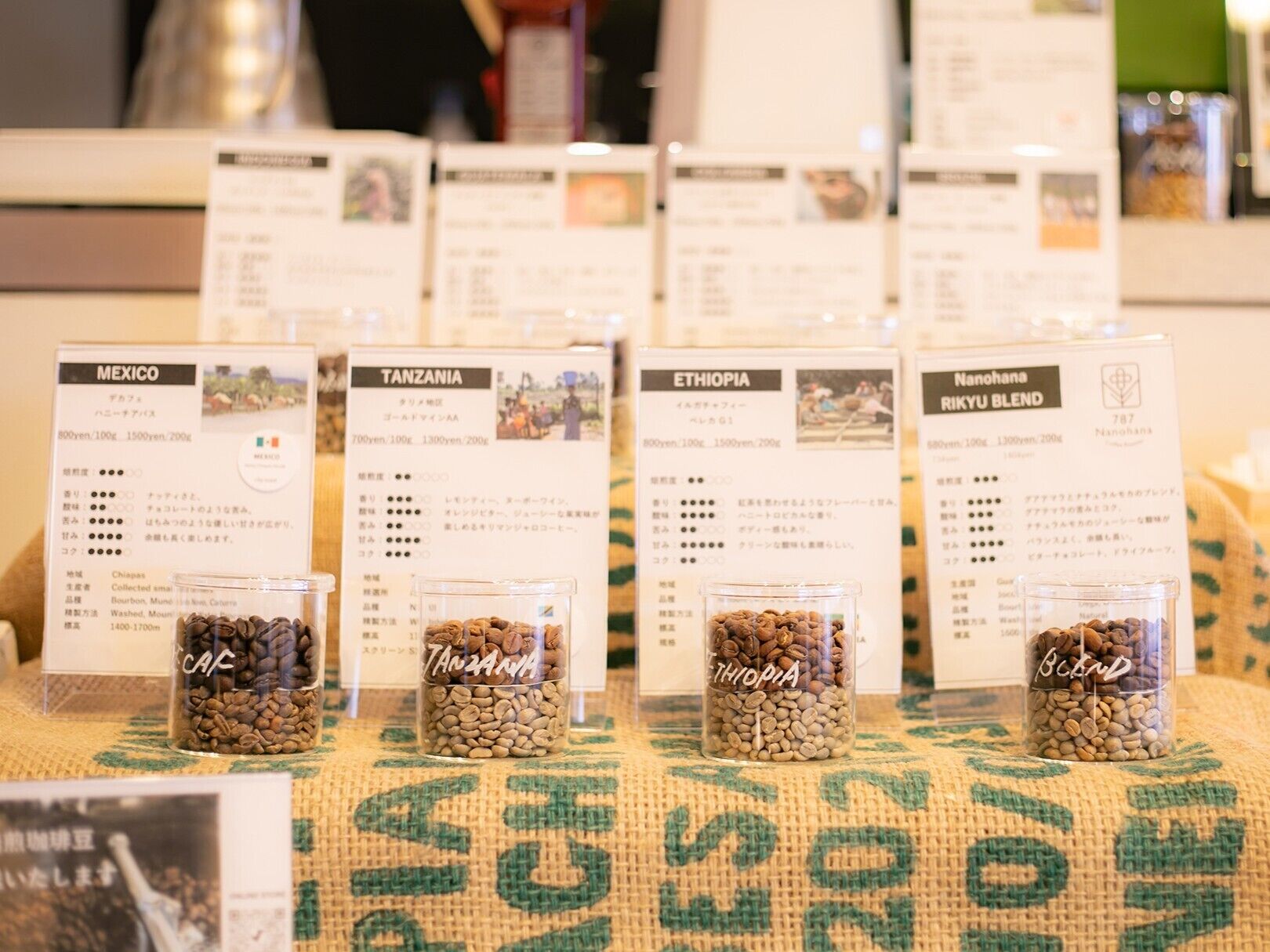 A display of coffee beans labeled with their origins: Mexico, Tanzania, Ethiopia, and Nanohana.