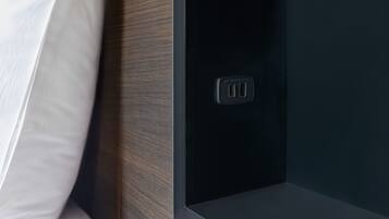 Primer plano de una pared oscura con un enchufe y una placa de interruptor rectangular pequeña.