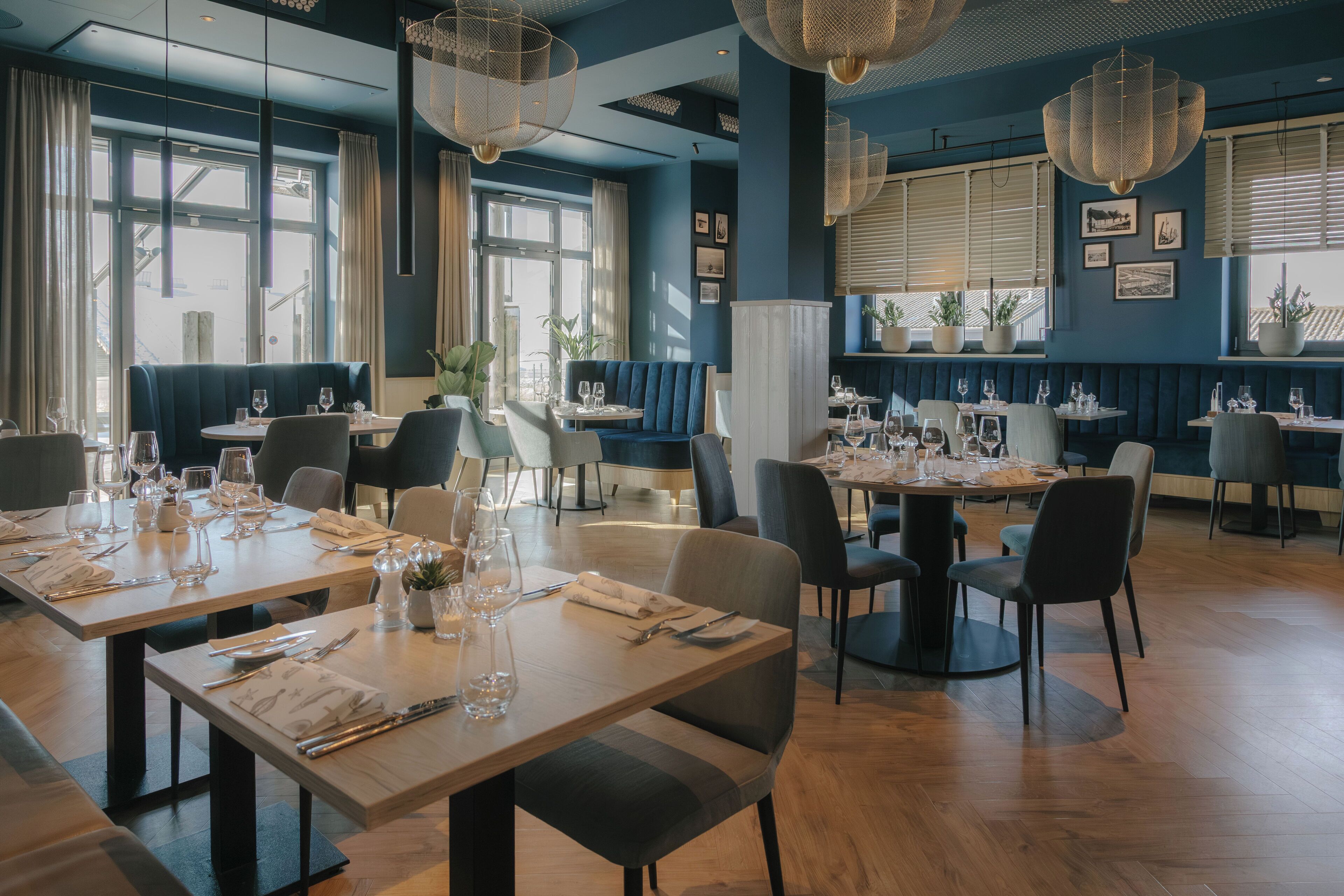 Ein Restaurant mit mehreren Tischen, Stühlen und hängenden Lampen.
