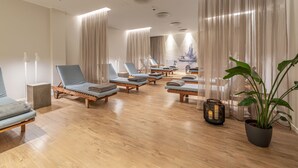 A spa room with wooden floors, multiple lounge chairs, and a large potted plant. - Küstenperle Strandhotel & Spa (Büsum)