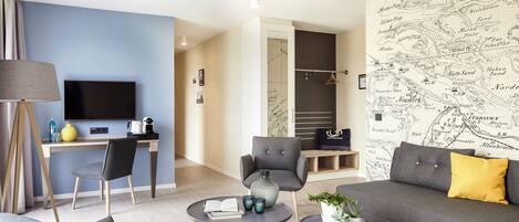 A modern living room with a sofa, coffee table, and chairs. There is a desk with a TV and a map on the wall.