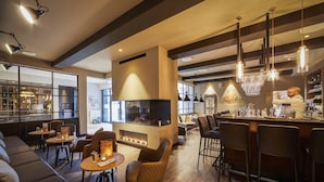 A modern bar area with seating, a fireplace, and a bar counter. - Küstenperle Strandhotel & Spa (Büsum)