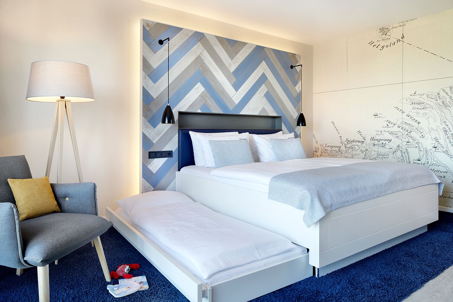 A modern hotel room with a large bed, a chair, a desk, and a map on the wall.