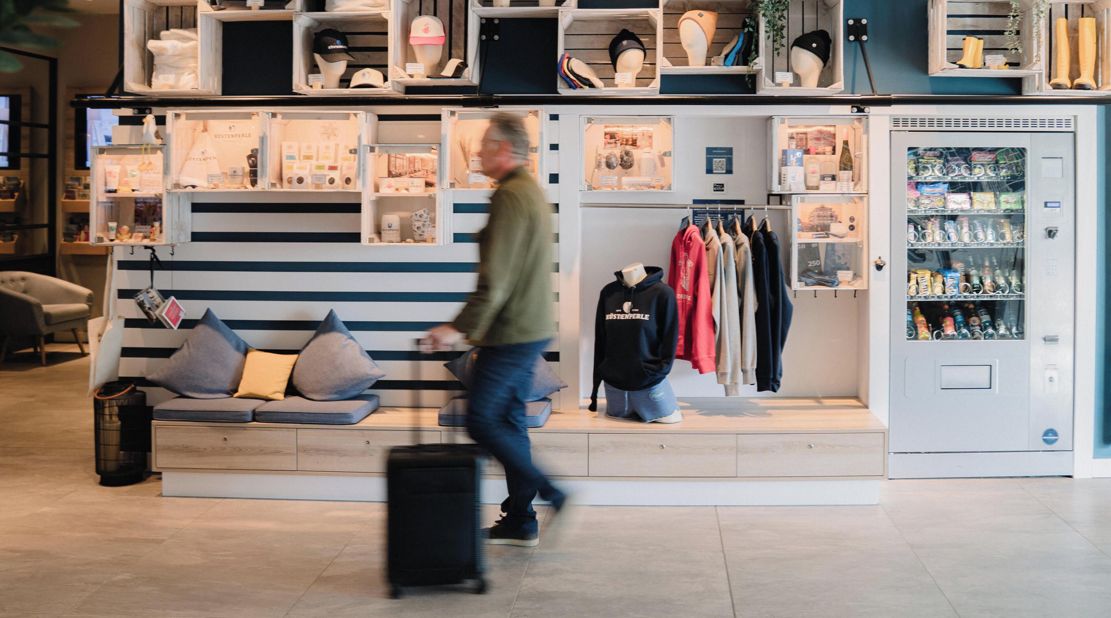 Un magasin avec des étagères remplies de chapeaux et de chaussures, un mannequin portant un sweat à capuche et un distributeur automatique.