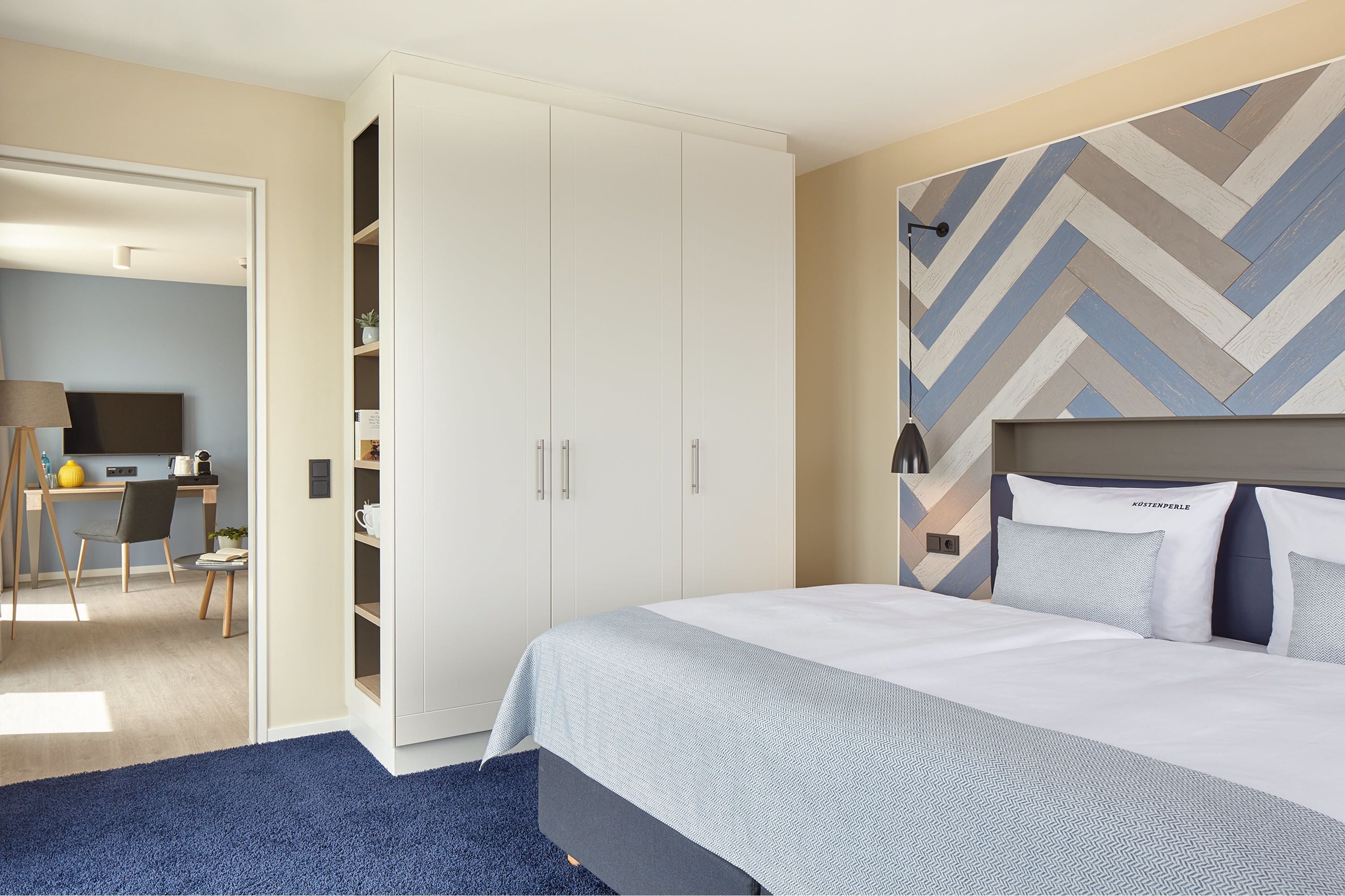 A hotel room with a bed, a wardrobe, a desk, and a chair.