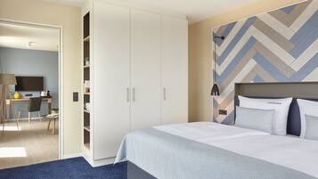 A hotel room with a bed, a wardrobe, a desk, and a chair.