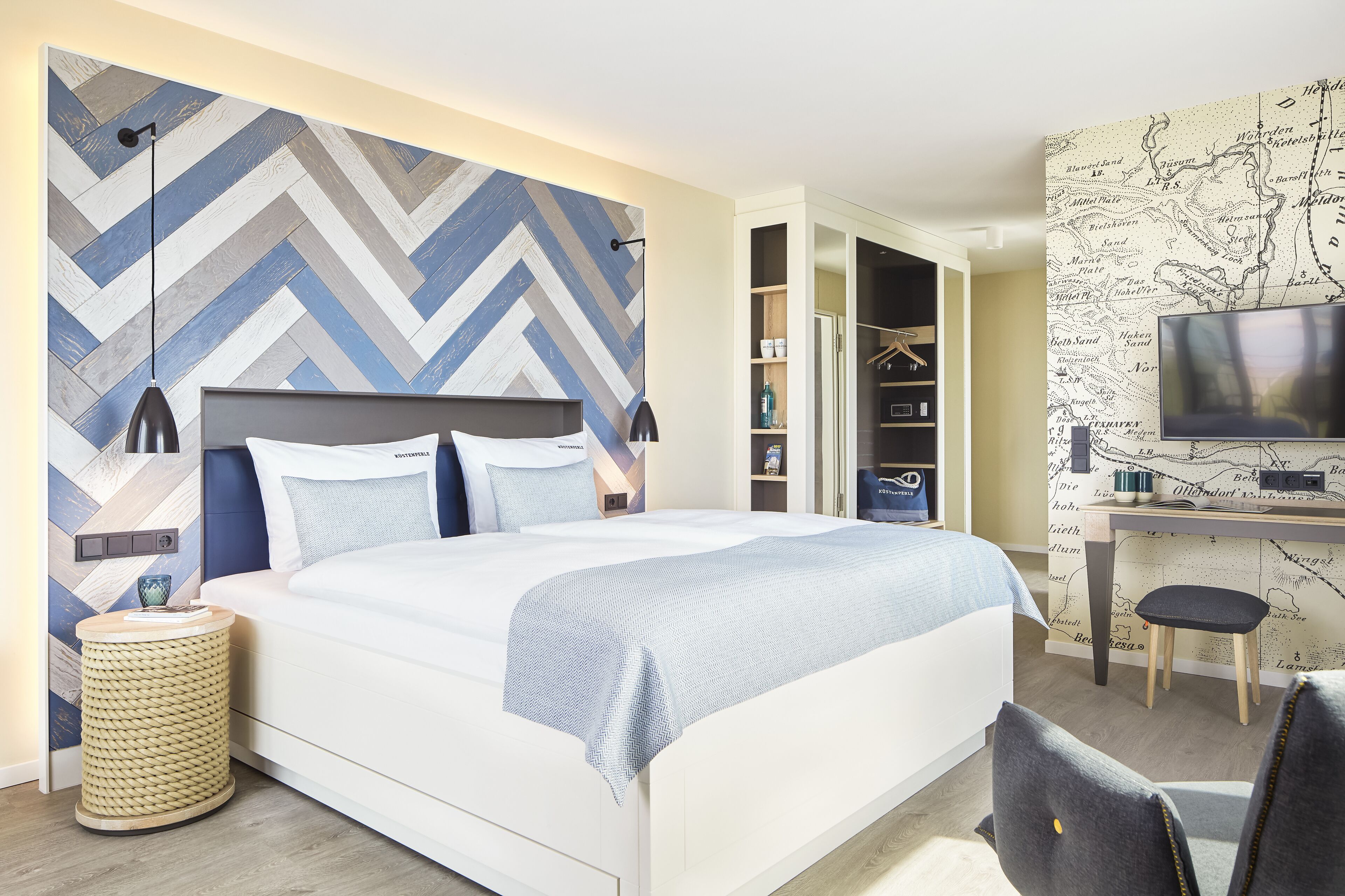 A modern bedroom with a large bed, a desk with a chair, a television, and a wardrobe.
