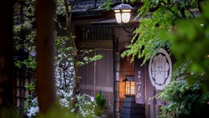 Un bâtiment traditionnel japonais, avec une entrée en bois, une lanterne et une enseigne ornée de caractères japonais.