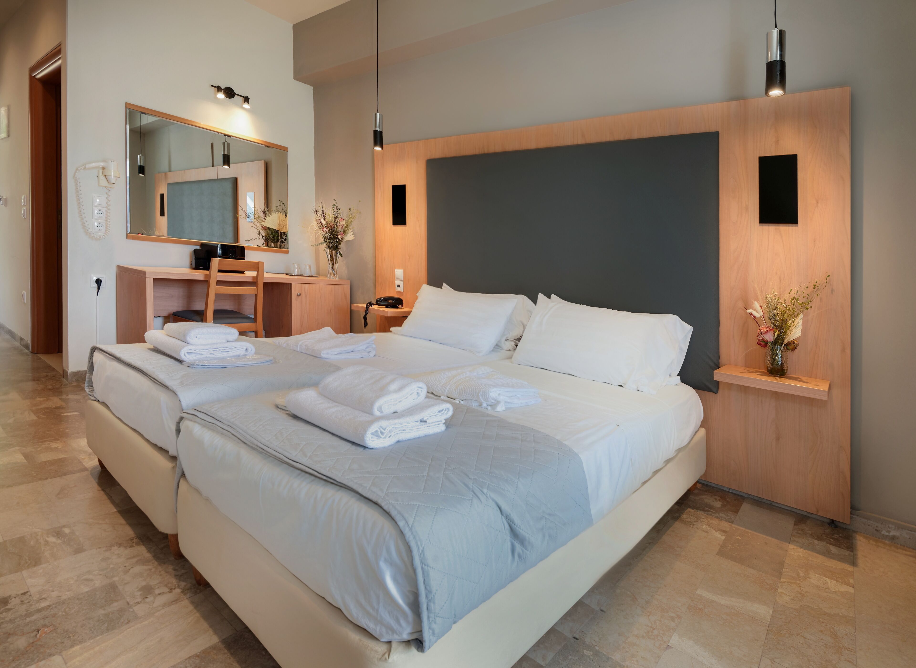 A modern hotel room with a large bed, a desk, and a mirror.