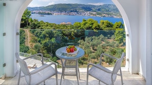 Ein Balkon mit Glastrennwand, ein runder Tisch mit Obstschale und Korbstühle.