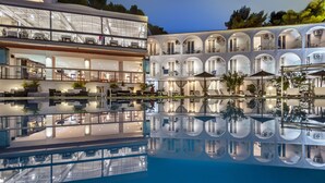 Ein modernes Hotel mit einem spiegelnden Pool, mehreren Speisebereichen und Außenplätzen.