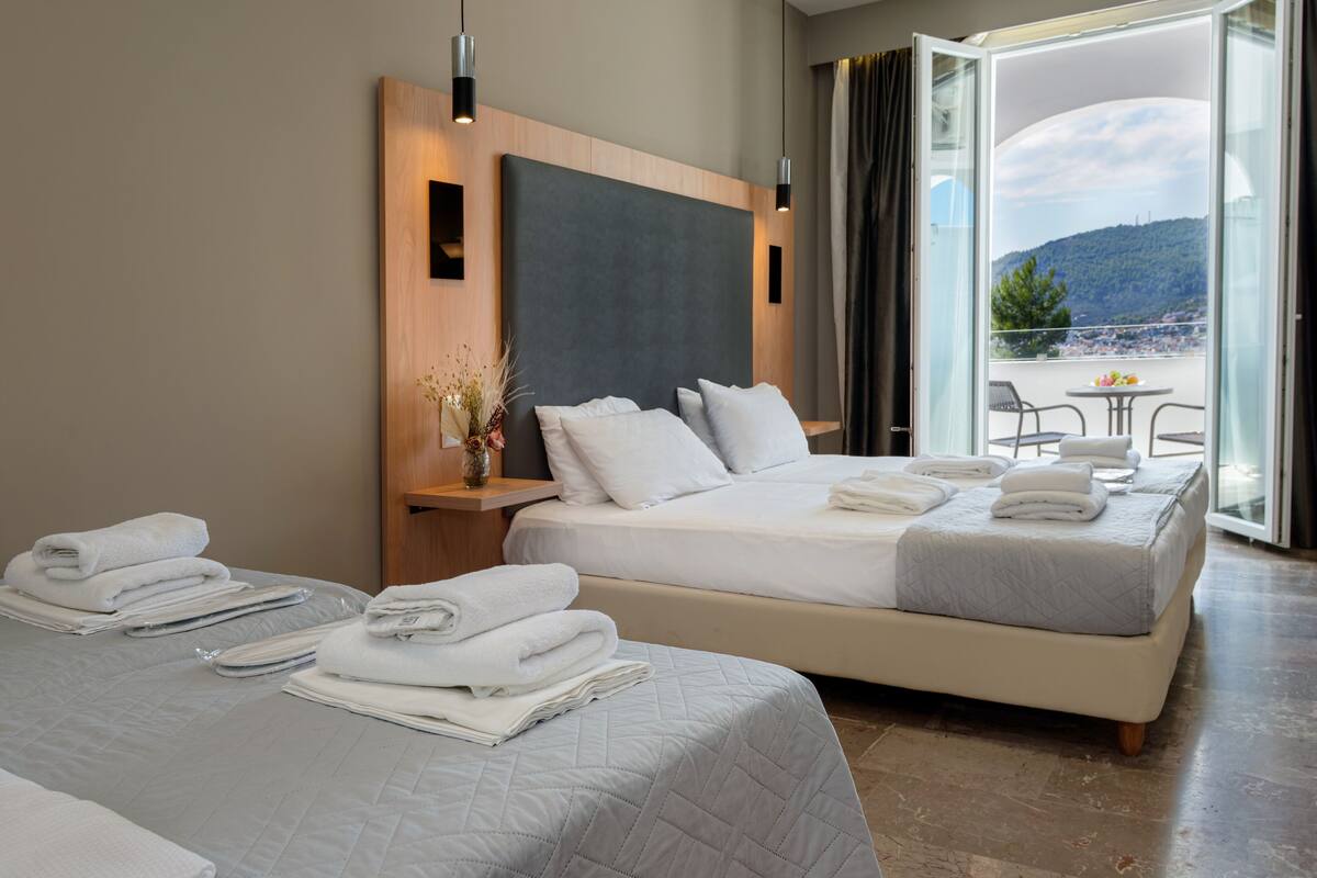 Ein Hotelzimmer mit zwei Betten, einem Balkon mit Tisch und Stühlen und Bergblick.