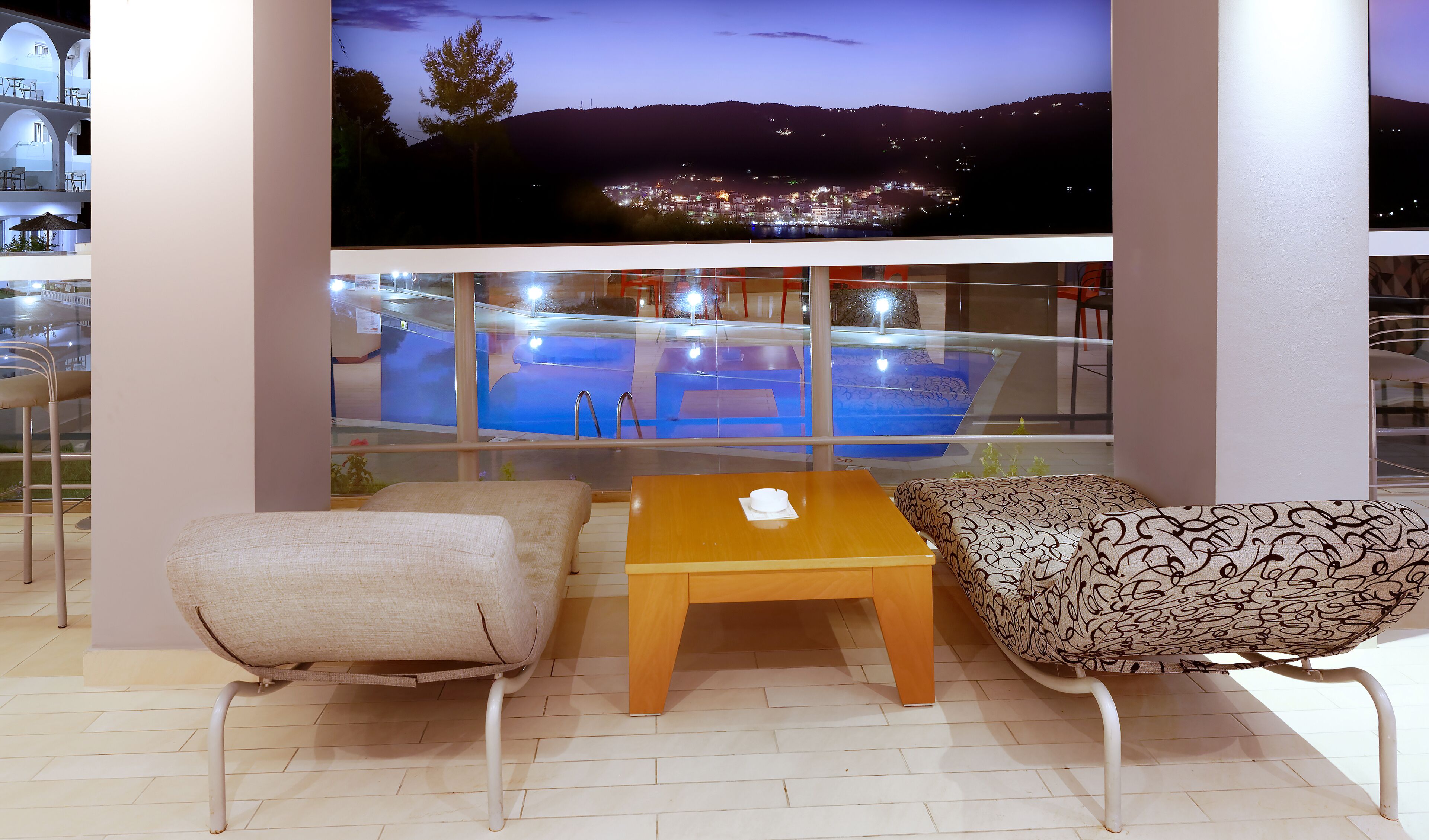 Un balcón con piscina, dos sofás y una mesa de madera.