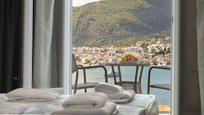Ein Hotelzimmer mit Balkon mit Blick auf eine Küstenstadt und Hügel.